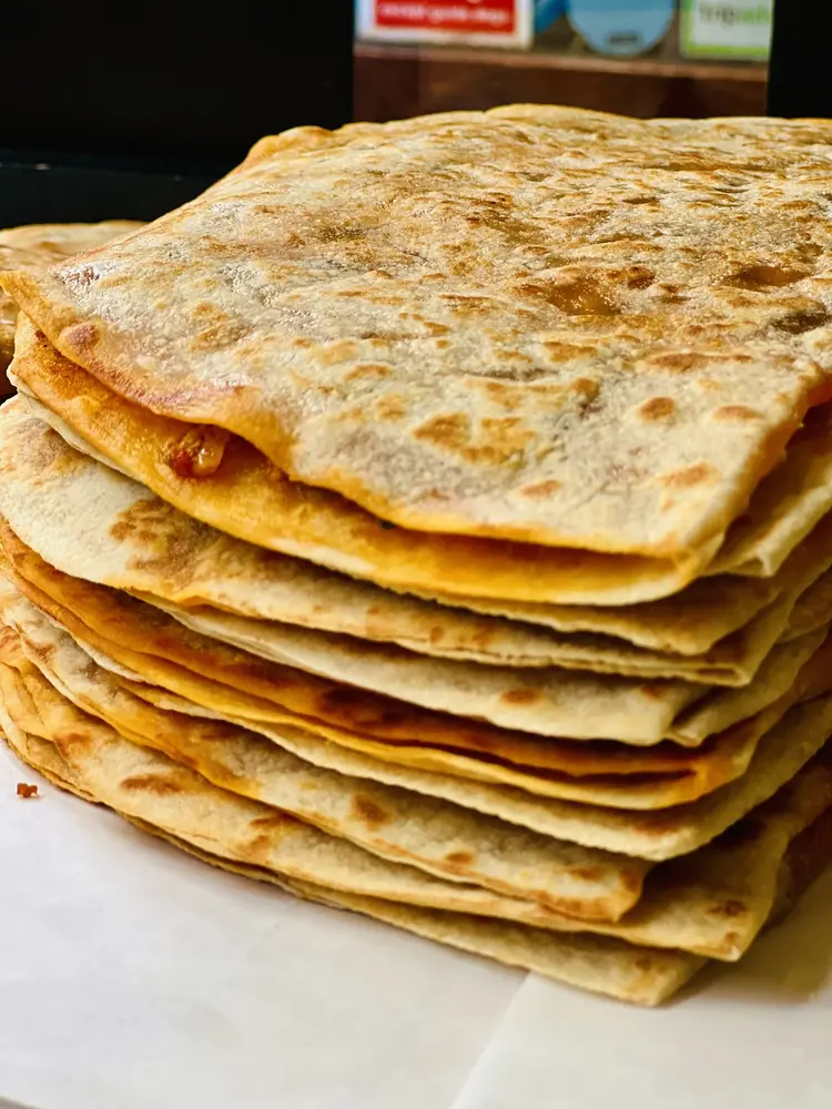 Stack of freshly griddled gözleme flatbreads with charred blistered edges