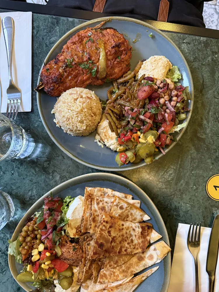 Grilled chicken shish with bulgur pilaf, hummus and chopped salad on a blue plate